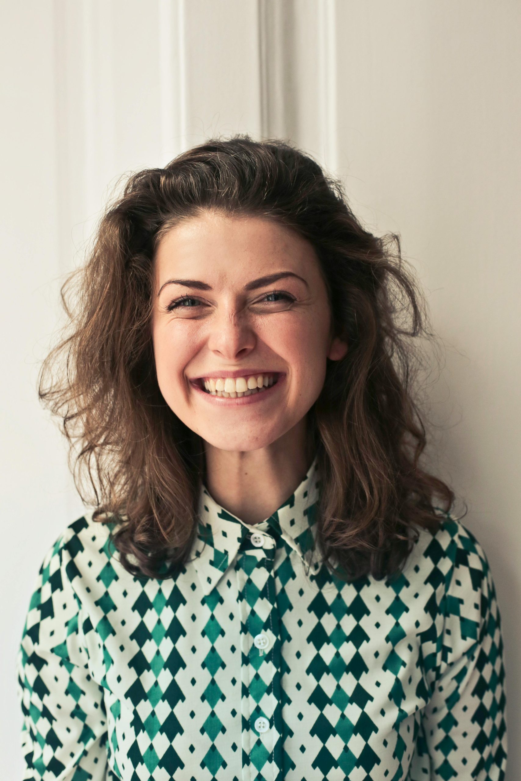 Portrait of a joyful brunette woman with a vibrant smile indoors, capturing happiness and positivity.